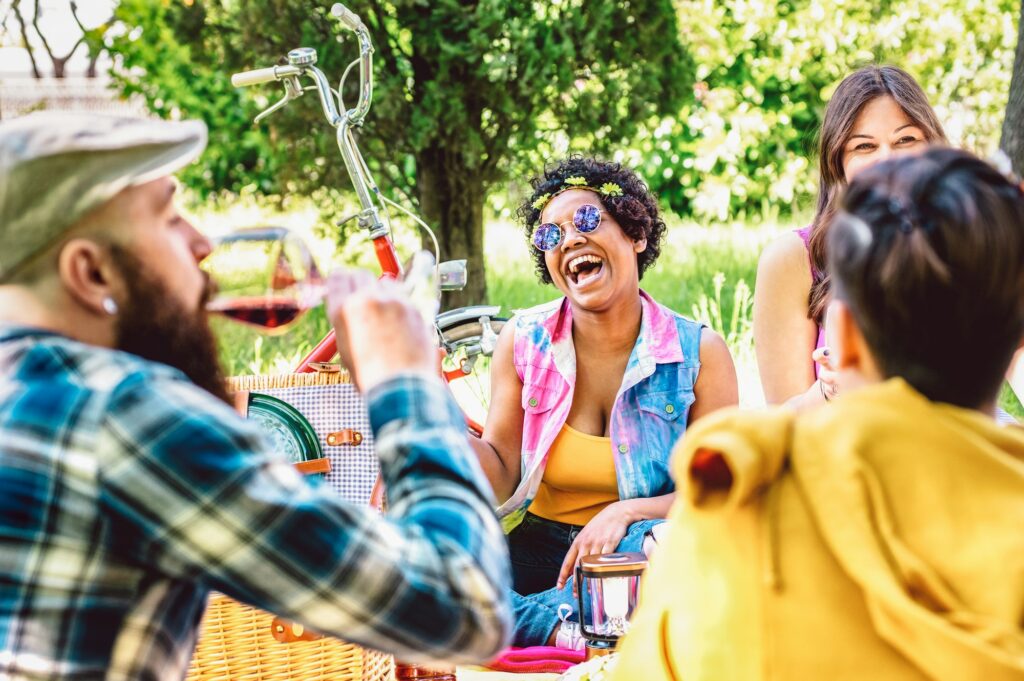 Happy friends having fun out side cheering at bbq picnic with fancy snacks food