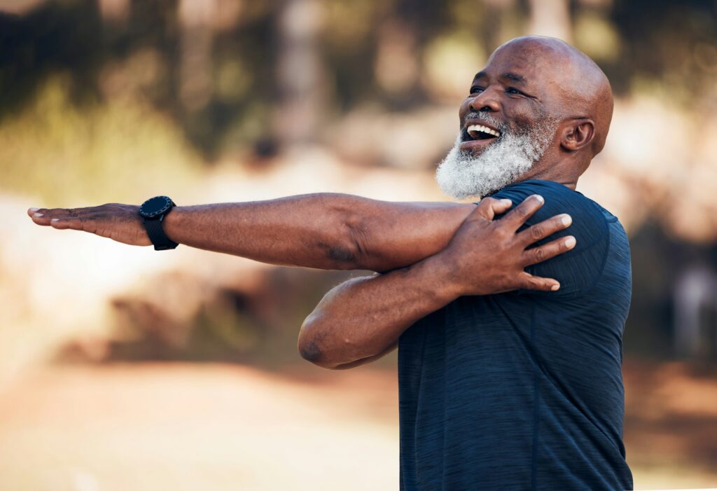 Black man, stretching and smile for exercise outdoor in nature forest for fitness and healthy lifes