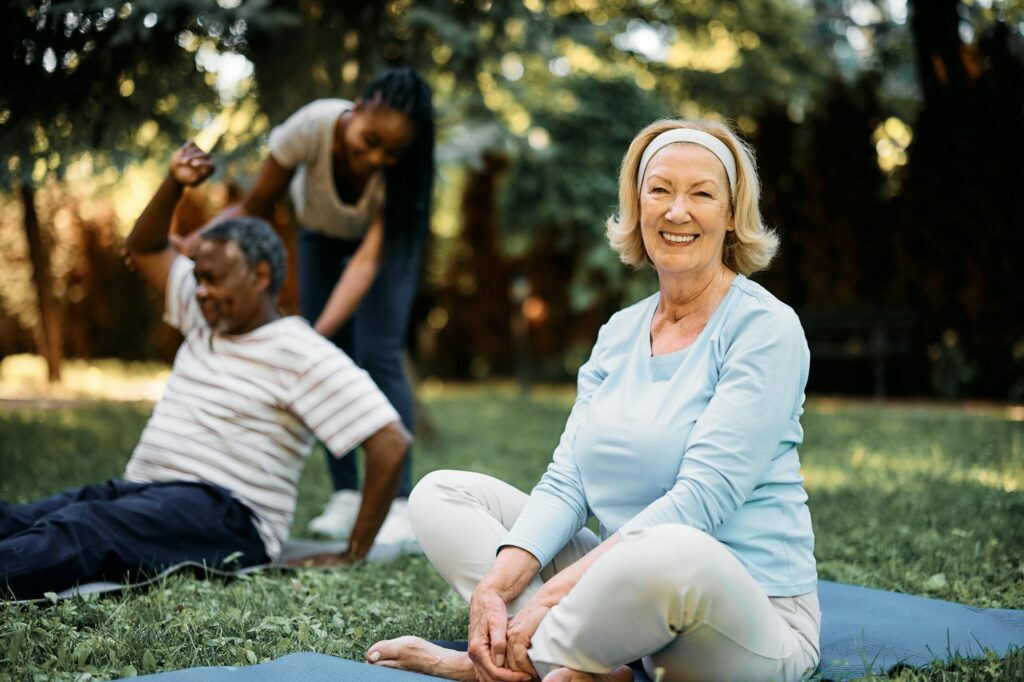 Happy senior woman having exercise class in nature and looking at camera.