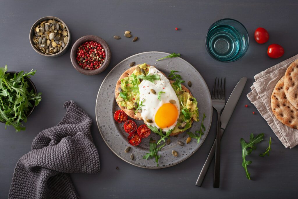 breakfast avocado sandwich with fried egg and tomato